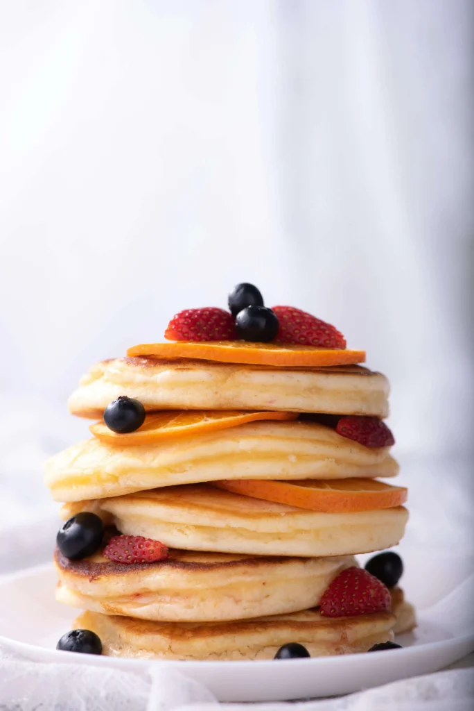Homemade berry pancakes topped with fresh fruit and syrup