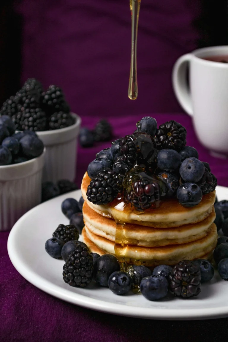 Fluffy berry pancakes topped with fresh blackberries and blueberries, drizzled with honey