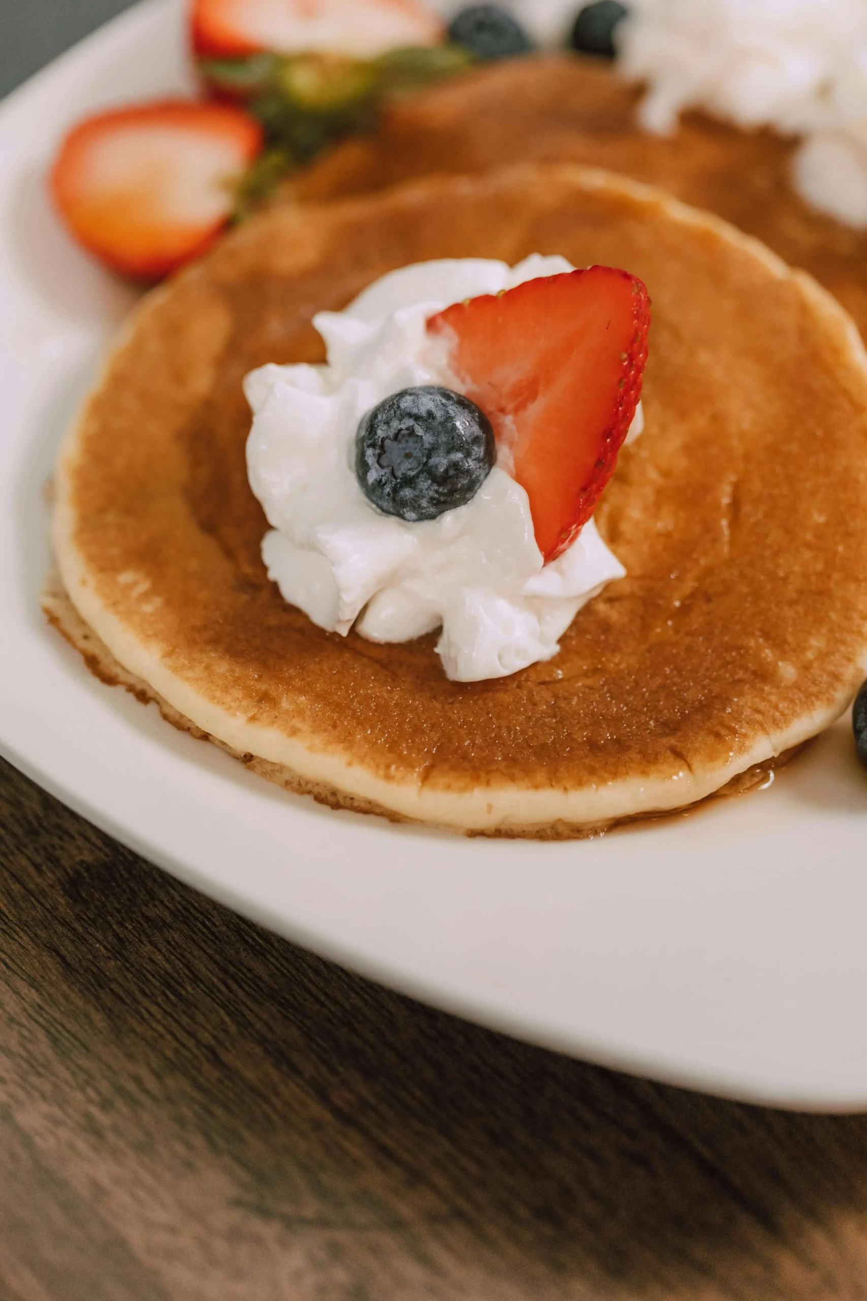 Breakfast Berry pancakes garnished with juicy berries and sweet honey