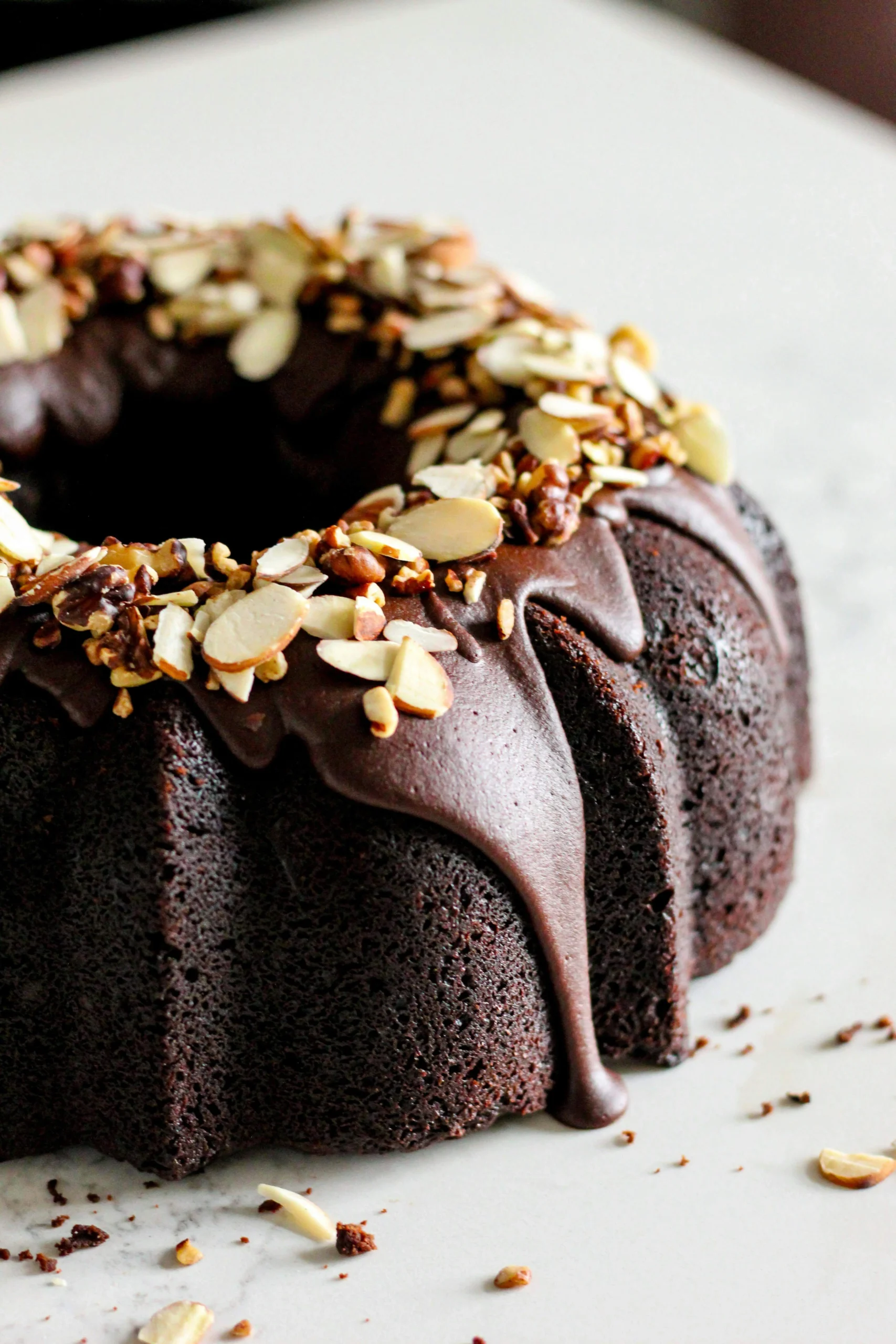 A slice of moist chocolate cake with rich, glossy chocolate frosting on a white plate.