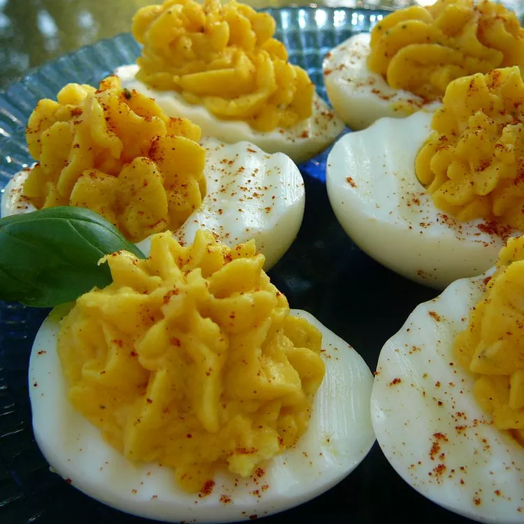 Devilled egg potato salad in a bowl, topped with paprika and fresh chives.