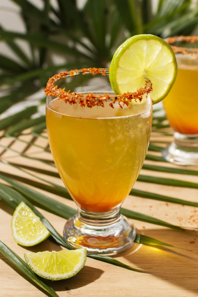 Fiery mango chili cocktail in an elegant glass with crushed ice and green sprigs.
