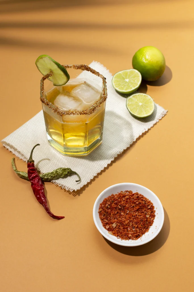 Fusion-style mango caipirinha cocktail with black seeds and leafy garnish, served chilled.
