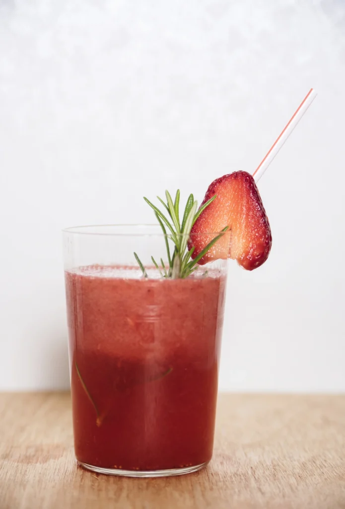Glass of Strawberry Lime Vodka Smash on a rustic table with fresh ingredients around.