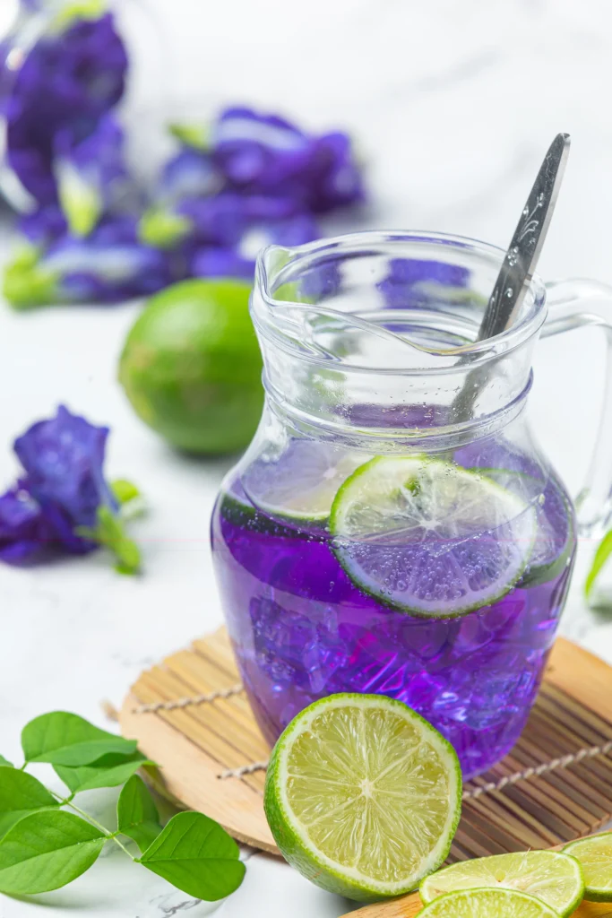 Purple Lavender Spritz mocktail with lime slices and butterfly pea flower.