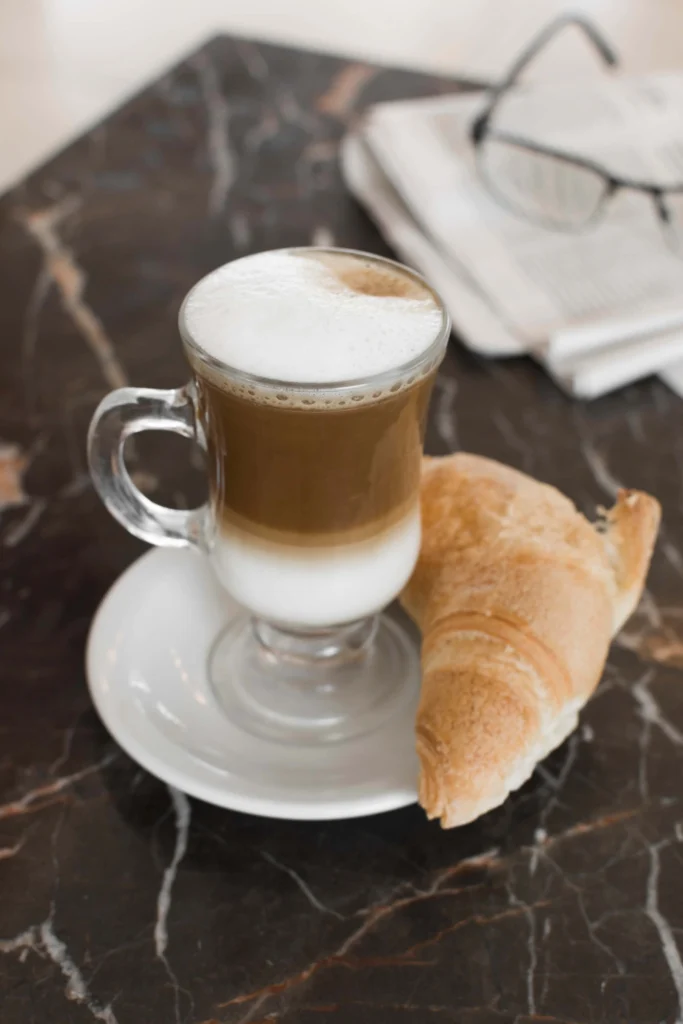 Cappuccino e Cornetto on white rustic table with condiments