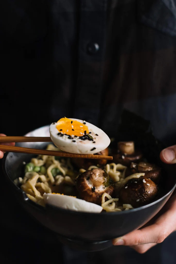 Healthy homemade ramen with rich broth, mushrooms, sprouts, and colorful toppings in a white bowl.