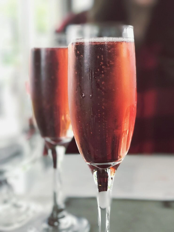 Close-up of a Kir Royal cocktail showing champagne bubbles and a lemon twist.