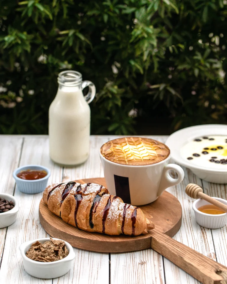 Cappuccino e Cornetto served on a wooden board with breakfast sides