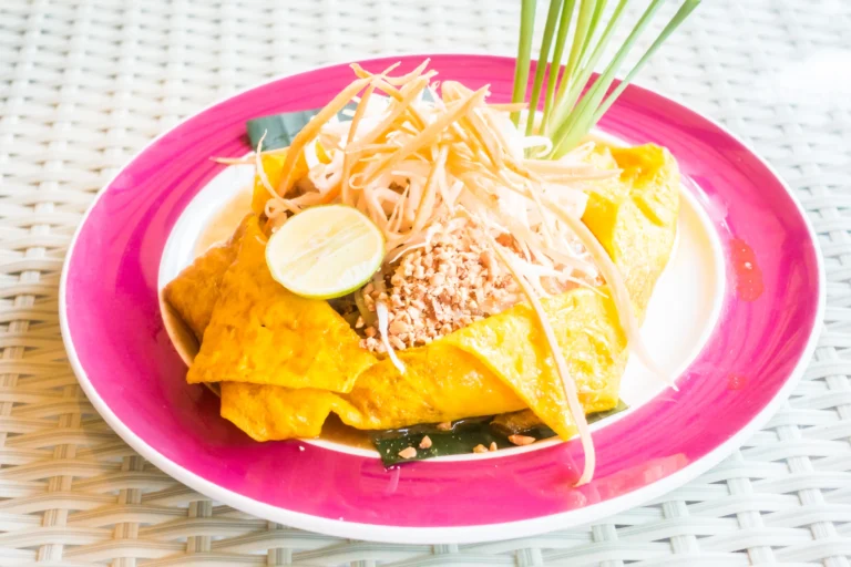 Traditional Cambodian rice noodle dish Nom Banh Chok with green fish curry and fresh herbs on a plate.