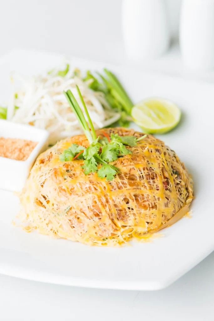 Colorful plate of Nom Banh Chok with noodles, curry, and crunchy vegetables on a rustic table.