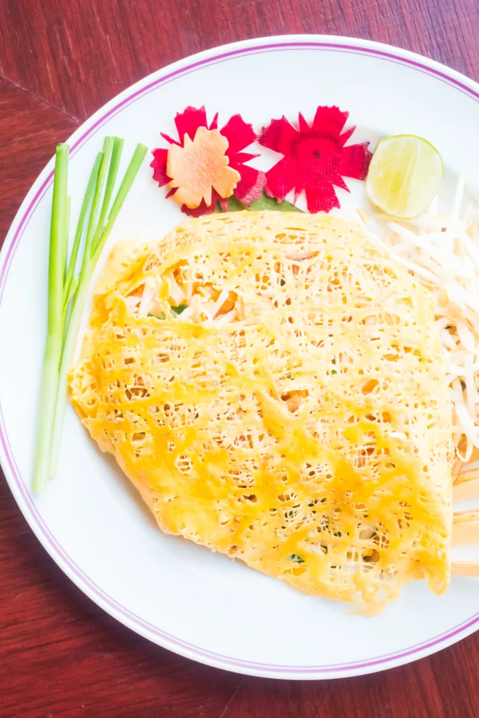 Cambodian Nom Banh Chok with green fish curry, herbs, and rice noodles served in a traditional bowl.