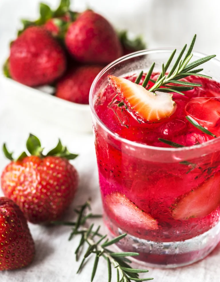 A refreshing Strawberry Lime Vodka Smash cocktail with fresh strawberries, lime slices, and mint leaves in a glass.