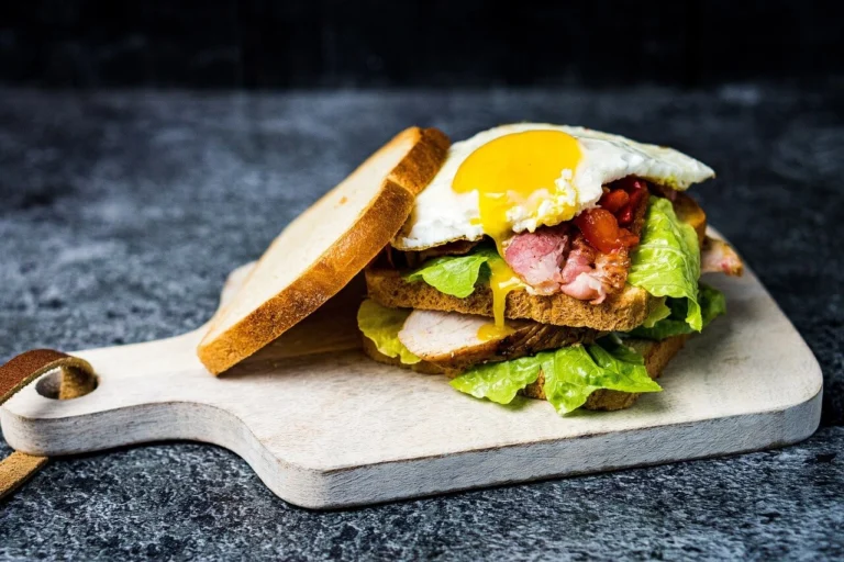 Avocado toast with a runny poached egg, chili flakes, and fresh herbs on toasted rustic bread.