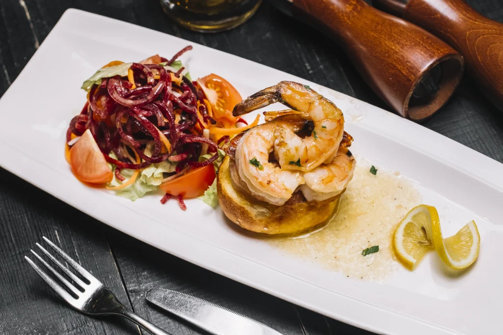 Close-up of Spanish garlic shrimp in olive oil with rustic bread.