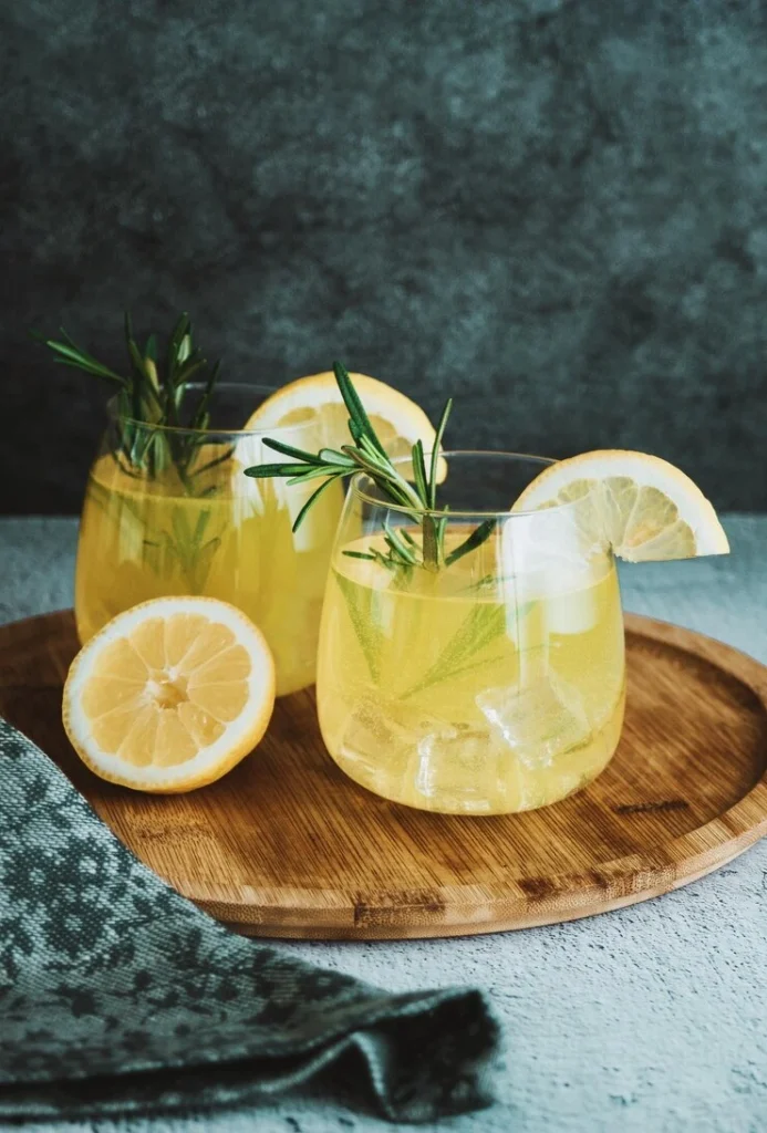 Elegant Limoncello Spritz served with ice and lemon wheel in a clear glass on a sunny patio table.