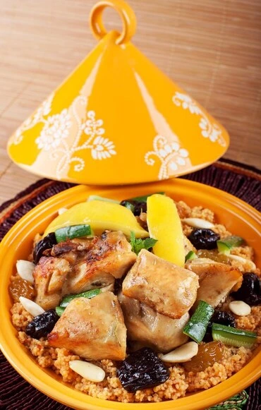 Slow-cooked Moroccan chicken with apricots, carrots, and peas in a rich sauce, served on a white plate with Christmas-themed decorations.