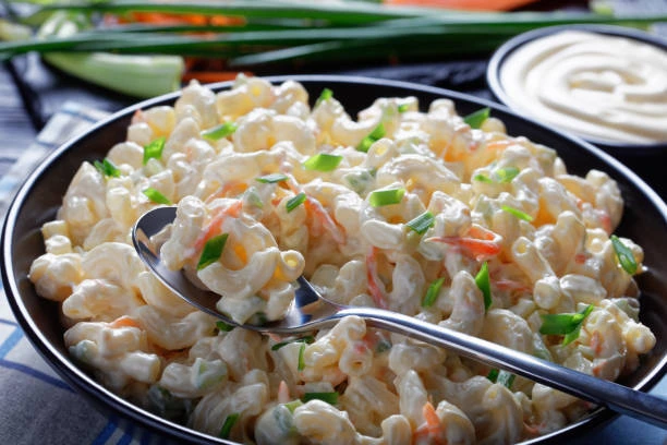 Homemade macaroni salad with mayonnaise and fresh herbs