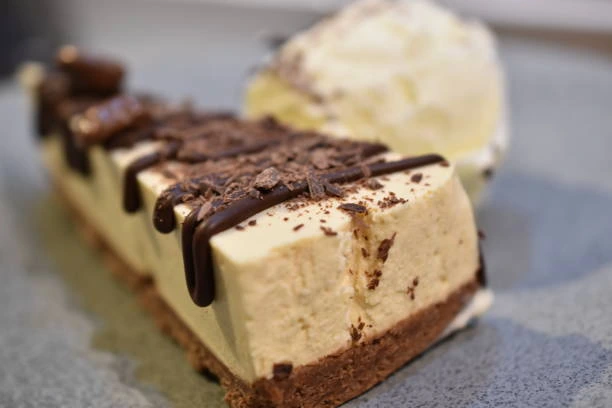 Baileys cheesecake slice on a plate with chocolate drizzle and whipped cream