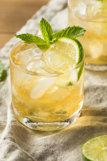 Refreshing Moscow Mule cocktail with ice, lime slices, and mint garnish in a clear glass on a linen cloth.