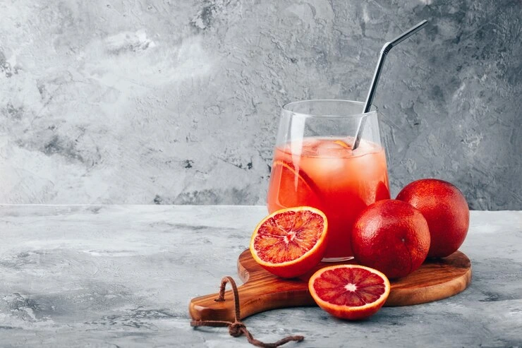 Campari Orange cocktail in a wine glass with an orange slice, mint garnish, and ice cubes.