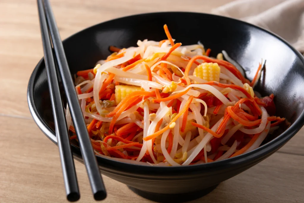 Traditional spring roll bowl salad with sticky rice and fresh vegetables on a marble surface.