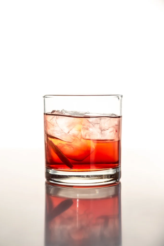 Amber Manhattan cocktail served in a martini glass with lemon garnish, ideal for menu display.