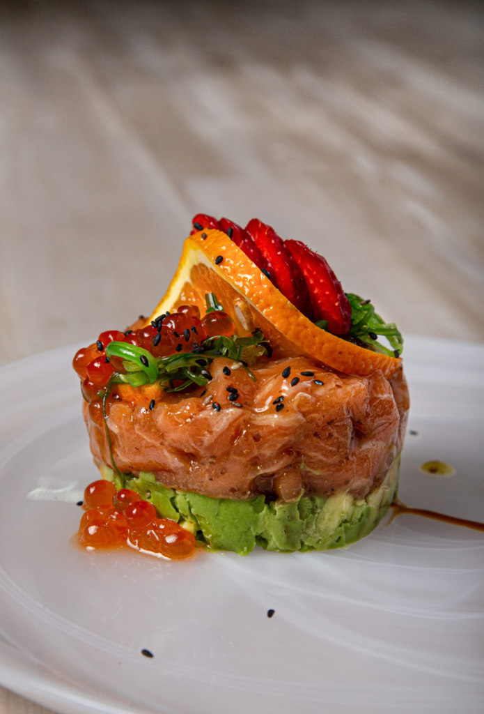 Seared Wild Alaskan Salmon topped with sauce, served with vegetable mash and tomato garnish.