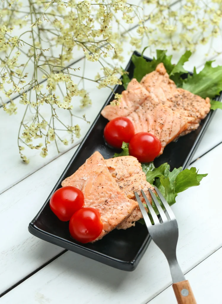 Wild Alaskan Salmon steak served with green mash and yellow sauce, garnished with tomato.